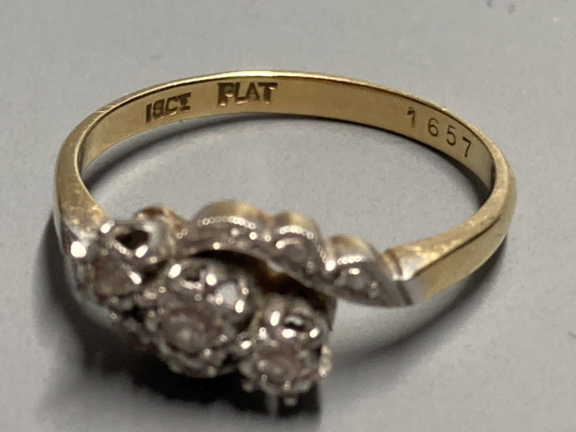 An 18ct and plat. illusion set three stone diamond crossover ring, size O/P, gross 3 grams.